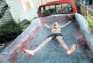 HEAT WAVE  ~~  Dave Bernier, of South Hadley, Mass., finds a creative way to beat the heat in the water-filled bed of his Ford pick-up truck Monday, July 5, 1999. Temperatures soared well into the 90s in western Massachusetts. (AP Photo/Union-News, Gretchen Ertl)